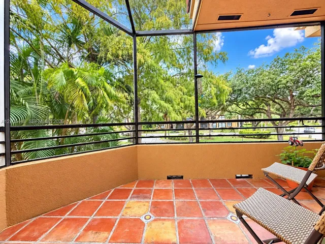 Screened-in balcony featuring terra-cotta tile flooring with decorative accent inlays, structured stucco wall, and metal frame enclosure