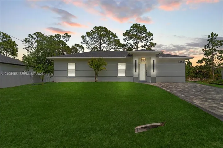 Modern exterior with horizontal siding, a paver driveway, and an established lawn