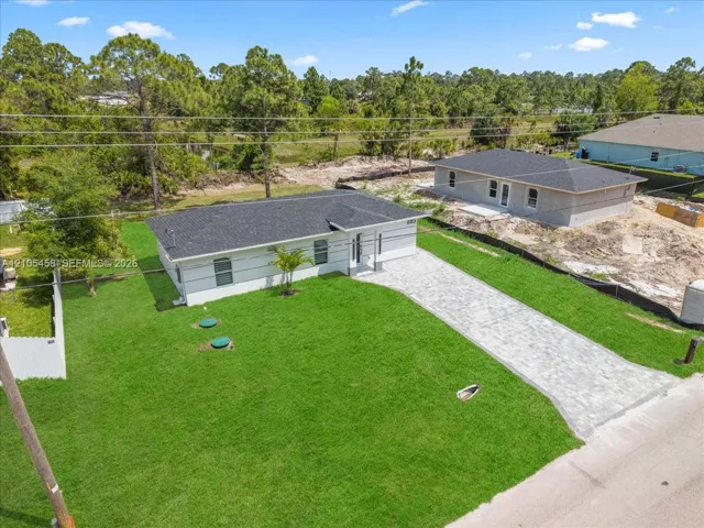 Contemporary residence with a dark shingle roof, white exterior siding, and a paver driveway