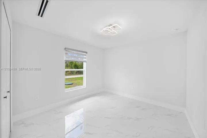 White tile flooring, modern ceiling light fixture, single window with blinds, white walls, and a white door with black hardware