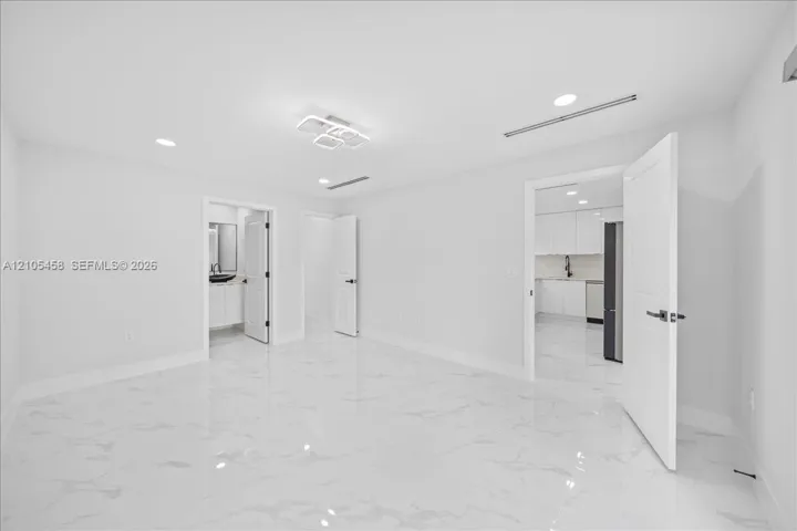 White tile flooring, recessed lighting, modern ceiling light fixture, white walls, white interior doors
