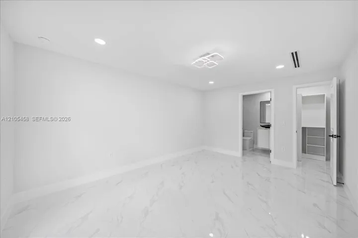Recessed lighting, contemporary ceiling fixture, polished tile flooring, built-in closet shelving, and a white vanity with a rectangular mirror