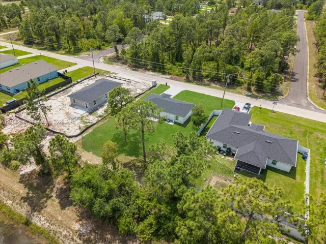Established residential property featuring a white privacy fence, an attached screened lanai, and a dark shingle roof