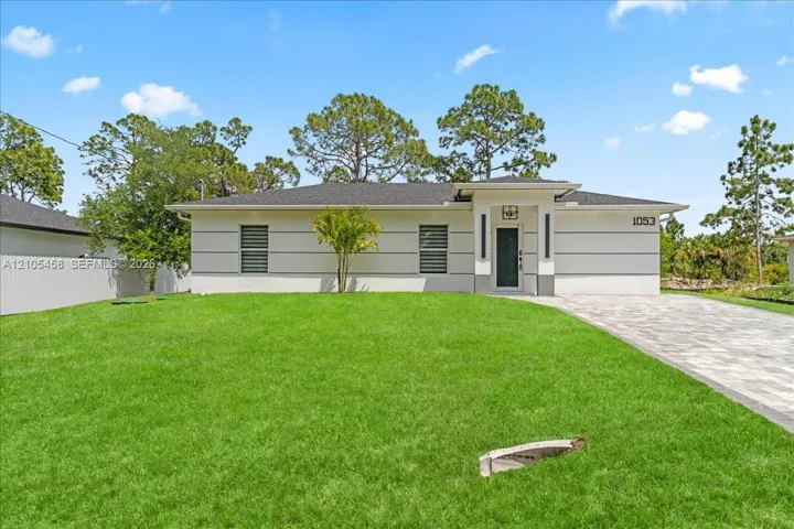 Contemporary-style exterior with a clean white and gray palette, dark entry door, and a paved driveway