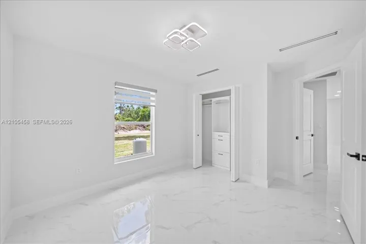 White tile flooring, modern ceiling light fixture, built-in closet storage, window with privacy blind, white panel doors