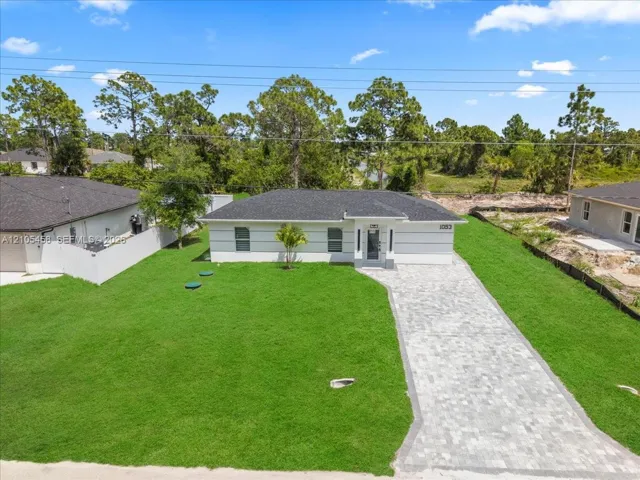 Contemporary single-story exterior with white siding, dark shingle roof, and paver driveway