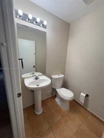 Pedestal sink with a chrome faucet, wall-mounted mirror, and vanity lighting