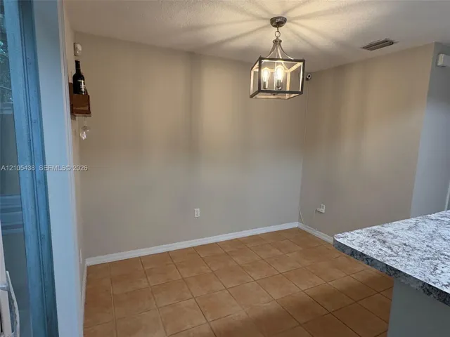Tiled flooring, overhead chandelier, light-toned wall finish, and a granite-finish countertop