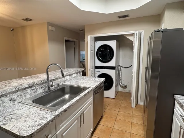 Kitchen featuring granite-look countertops, a stainless steel sink with a high-arc faucet, white cabinetry, and stainless steel appliances