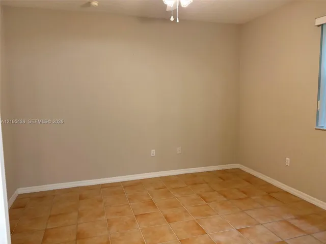 Neutral tone wall finishes, tiled flooring, white ceiling fan, and window with vertical blinds
