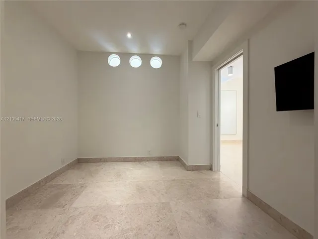 Recessed ceiling lighting, three flush-mount wall sconces, neutral wall paint, and stone tile flooring