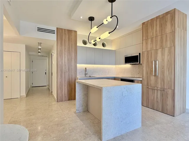Modern kitchen featuring wood-finish cabinetry, a waterfall island, and recessed lighting