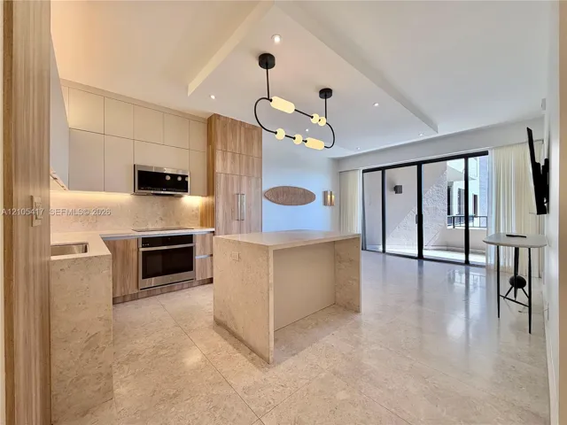 Contemporary kitchen with integrated appliances, light-toned cabinetry, and a stone-clad island