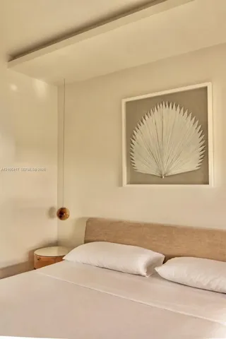 Recessed ceiling panel, fabric upholstered headboard, suspended spherical light fixture, and wood-finish side table with white top