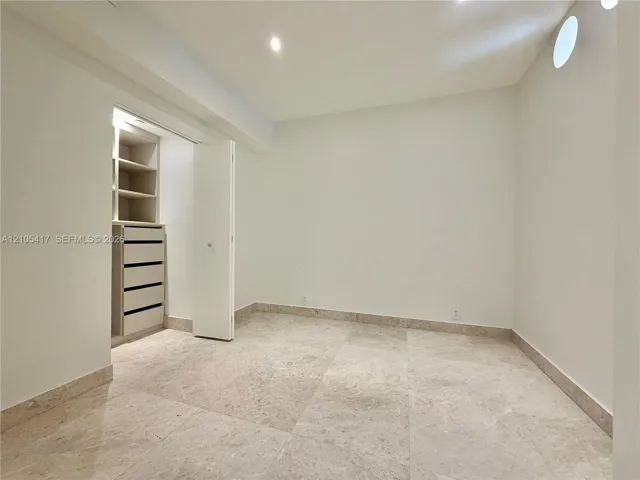 Recessed lighting, built-in closet storage with drawers, built-in shelving, a round window, and large format tile flooring