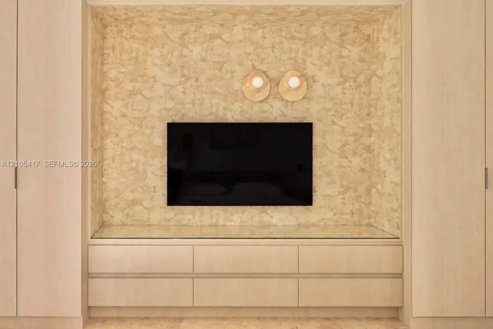 Integrated entertainment center with textured wall finish, wood-finish cabinetry, and glass countertop