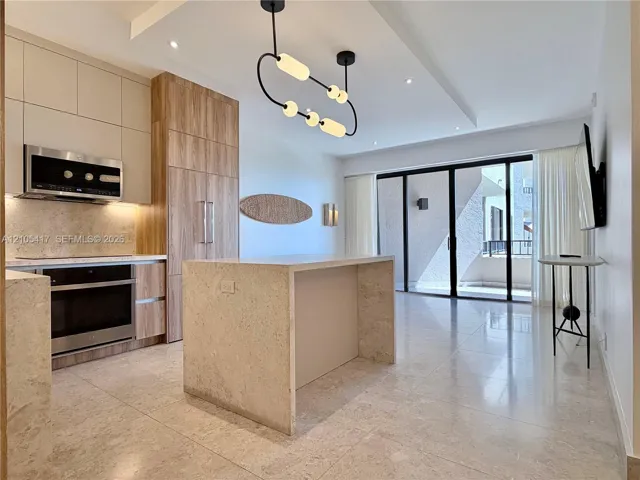 Modern kitchen featuring wood-finish cabinetry, stainless steel appliances, and a waterfall island with integrated seating