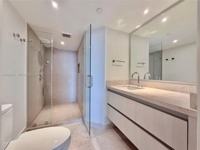Floating vanity with a light-toned countertop, under-mount sink, and contemporary faucet