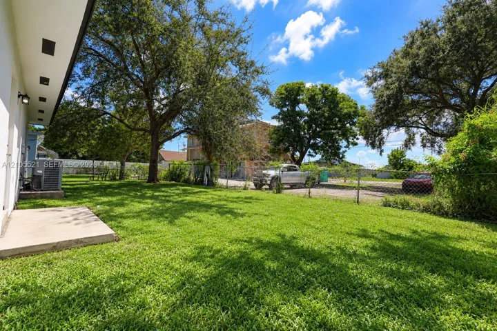 Expansive green lawn with mature trees and a concrete patio