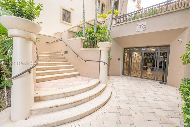 Tiered staircase with wrought iron handrails, leading to an entrance with security gates