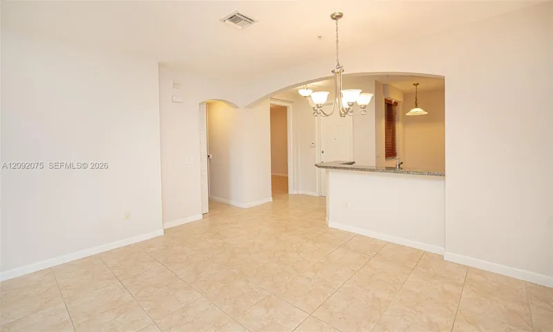 Tiled flooring throughout, arched doorways, a built-in breakfast bar with a stone countertop, and an overhead chandelier light fixture