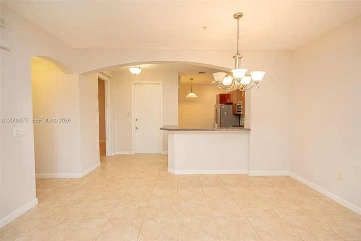 Tile flooring, overhead chandelier, arched doorways, breakfast bar, and stainless-steel appliances