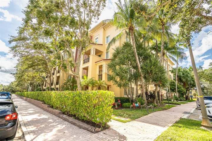 Multi-story residential structure with a stucco exterior, multiple private balconies, and a tile roof