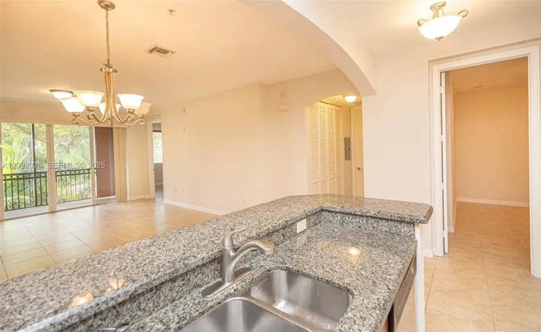 Kitchen counter with a double stainless steel sink, granite-finish countertop, and a chrome faucet