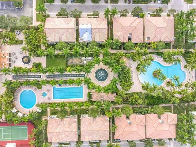 Community grounds featuring multiple pools, a tennis court, and lush landscaping