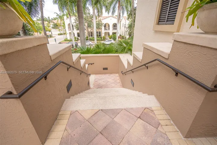 Exterior staircase with stucco walls, integrated wall lighting, and wrought iron handrails