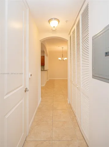 Hallway featuring square tile flooring, louvered bi-fold doors, and an arched doorway