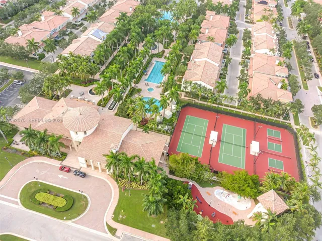 Expansive community grounds featuring a tennis court, two swimming pools, a clubhouse with a circular tower, and a designated splash pad area