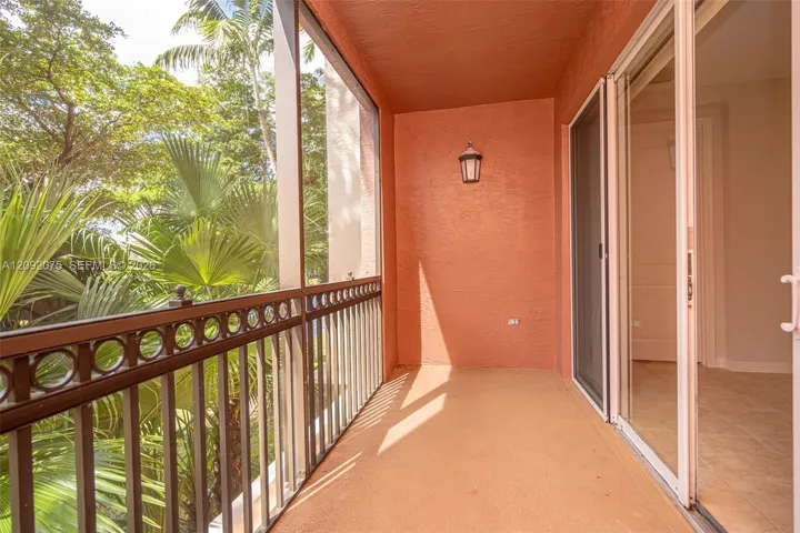 Balcony featuring a decorative metal railing, exterior wall sconce, and sliding glass doors