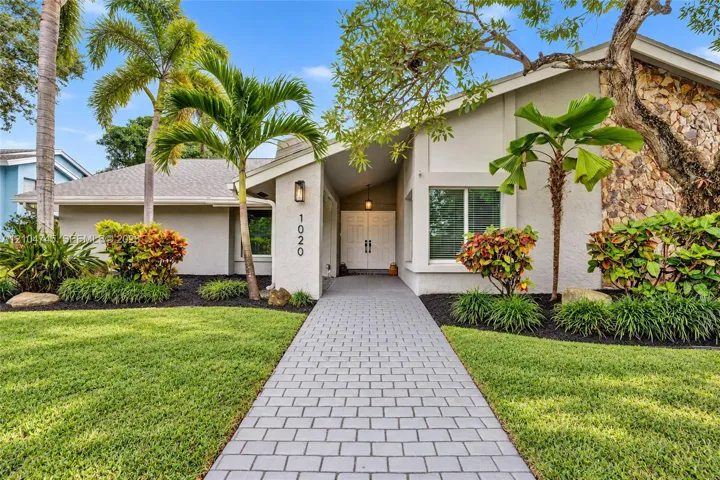 White stucco exterior with stone accents, featuring a gray paver walkway