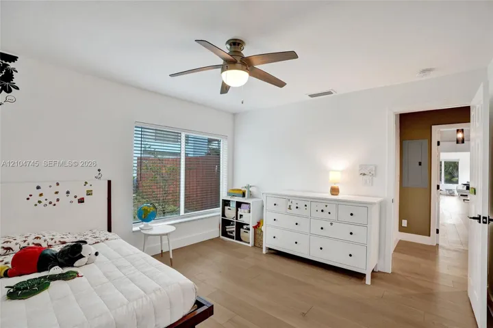 Wood-finish flooring throughout, white walls, and a recessed window with blinds