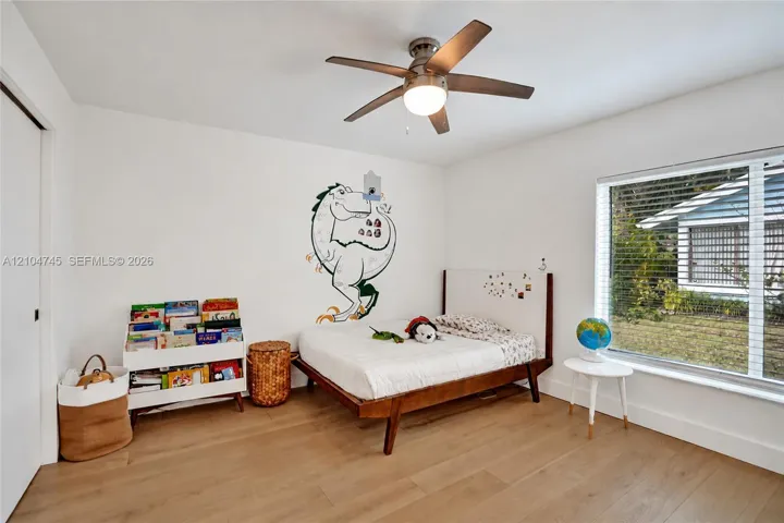 Wood-finish flooring, white walls, and a ceiling fan with integrated lighting