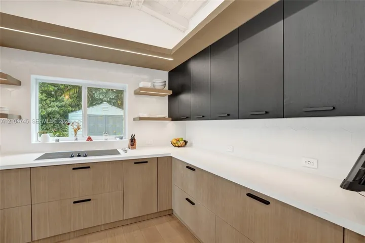 Modern kitchen featuring wood-finish lower cabinetry, dark-finish upper cabinetry, white countertops, and a white hexagonal tile backsplash