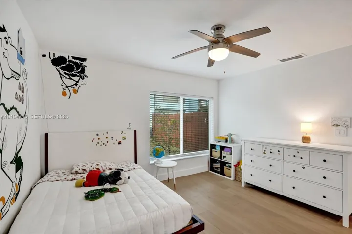 Recessed window with blinds, wood-finish flooring, and a ceiling fan with integrated lighting