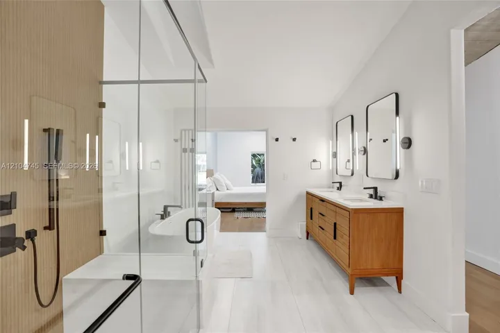 Dual vanity with wood-finish cabinetry, white countertops, and matte black fixtures