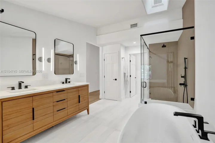 Dual vanity with wood-finish cabinetry, white countertop, and matte black fixtures