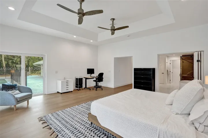 Recessed lighting, tray ceiling, two ceiling fans, wood-finish flooring, and sliding glass doors to the exterior