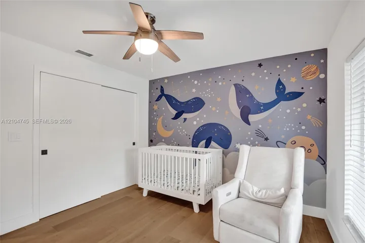 Wood-finish flooring, ceiling fan with integrated lighting, built-in closet with sliding doors, and window with horizontal blinds