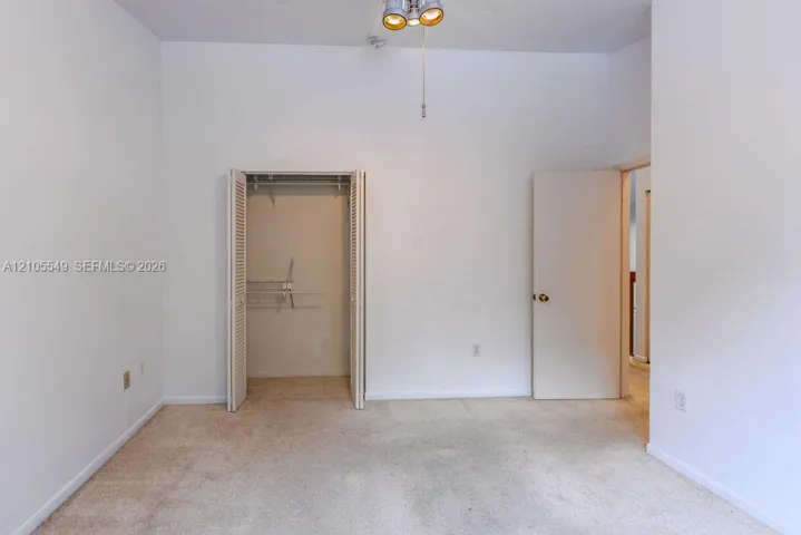 Carpeted flooring, white walls, bi-fold closet doors, integrated ceiling light fixture, interior door with brass hardware