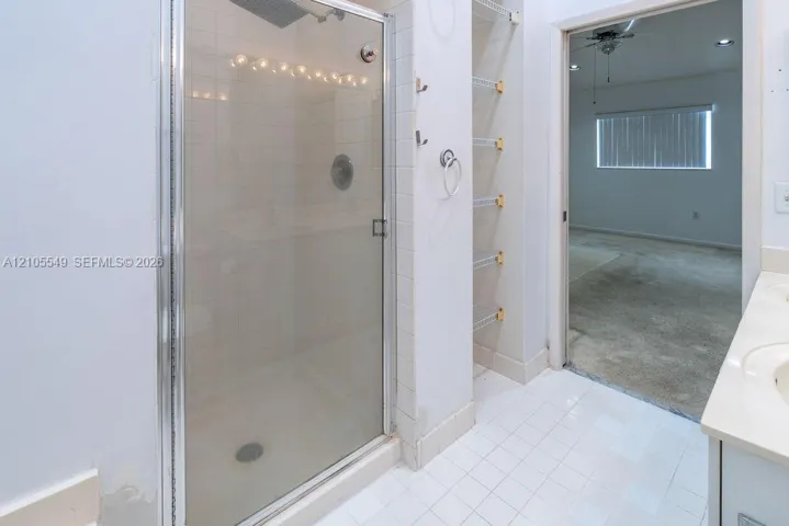 Walk-in shower with clear glass enclosure and overhead lighting