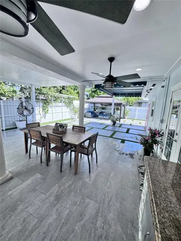 Covered patio with integrated ceiling fans, recessed lighting, and a built-in outdoor kitchen featuring a granite countertop