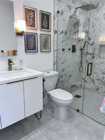 Walk-in shower with glass enclosure, herringbone tile, and rain shower head