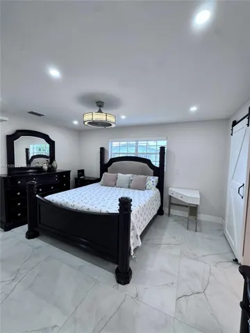 Recessed lighting, ceiling fan with integrated light, marble-look tile flooring, and a white barn door