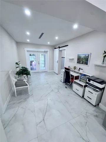 Recessed lighting illuminates the space, featuring large format tile flooring and a white barn door