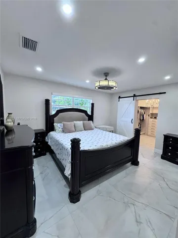 Recessed lighting with a ceiling fan, window with glass blocks, white wood-finish barn door, and large format tile flooring