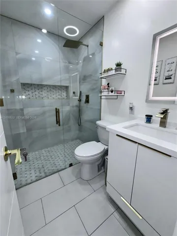 Glass-enclosed shower with a rainfall showerhead, integrated shower niche, and mosaic tile flooring